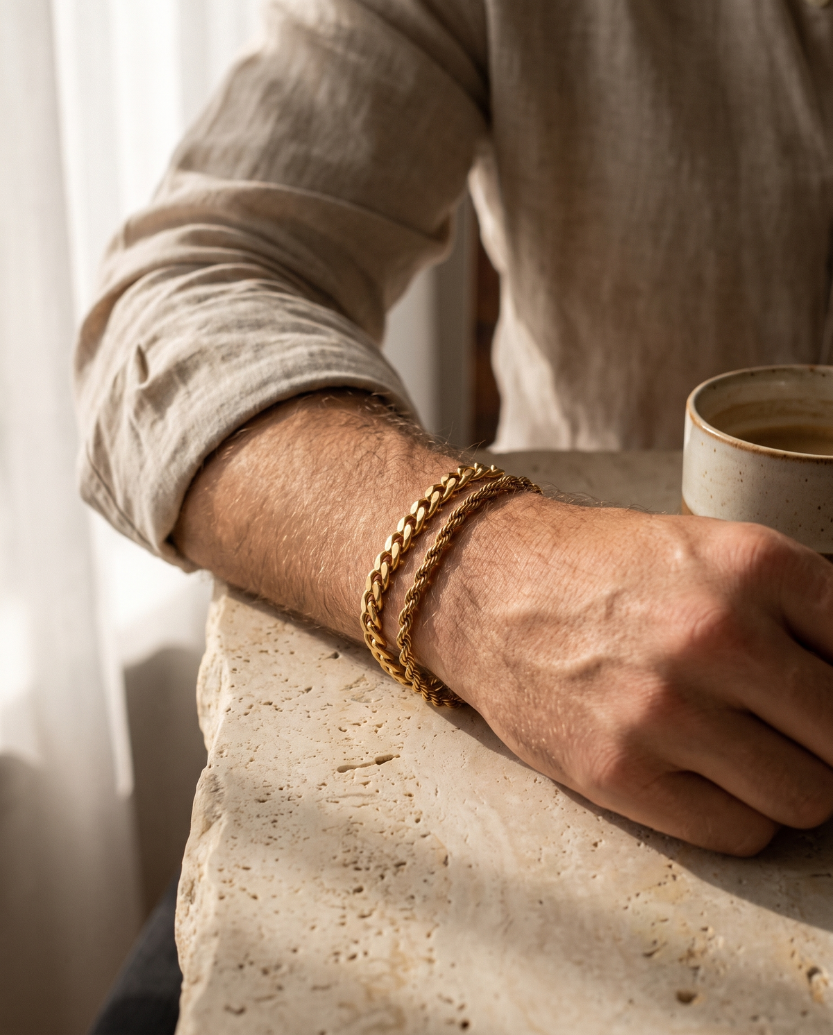 Sablon Stack in gold worn on the wrist, forearm on a stone table